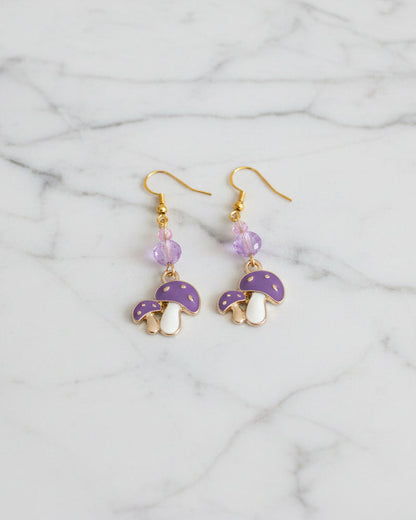 Enchanting mushroom earrings featuring delicate crystal beads nestled on lustrous gold plated hooks. Each earring measures approximately 2 inches, striking the perfect balance between statement-making and wearable elegance. At just 0.15 oz per pair, these lightweight beauties won't weigh you down, making them ideal for all-day wear. The shimmering gold plating catches the light beautifully, while the crystal accents add a touch of sparkle and sophistication. 