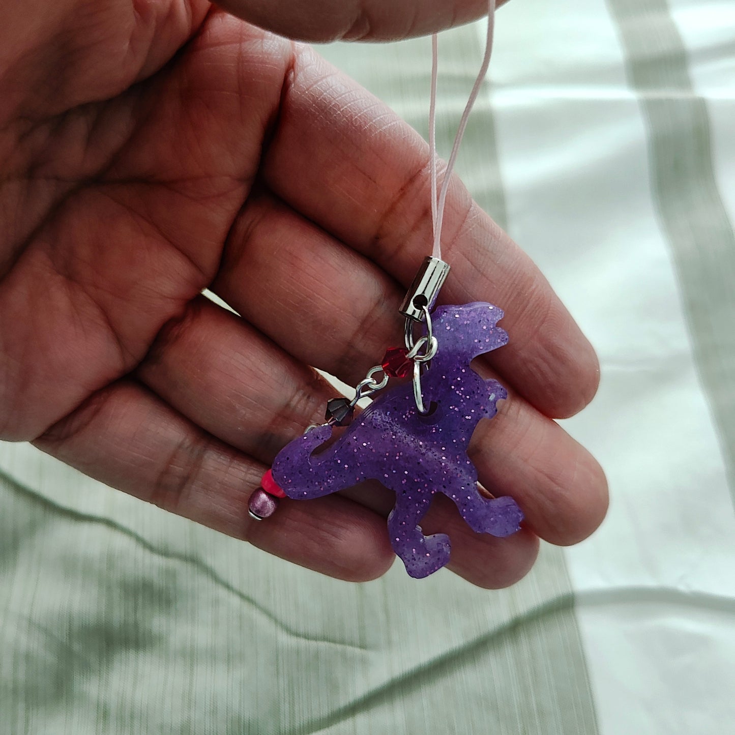 Add some roar to your phone with this T-Rex-resin dinosaur charm! With colorful beads for extra pizzazz, this charm will have everyone dino-swooning over your phone. Don't let your phone be extinct of style - grab this charm today!