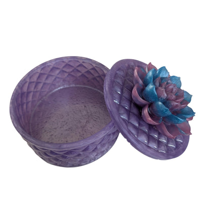 Keep your tiniest treasures safe in our round trinket box. With a charming resin design and a beautiful flower lid, it adds a playful touch to any space. At approximately 5 x 5 in, 4.25 in height, and weighing 11.7 oz, it's perfect for your precious items.