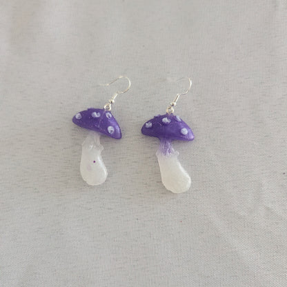 Pair of purple and white mushroom-shaped earrings on a light gray background