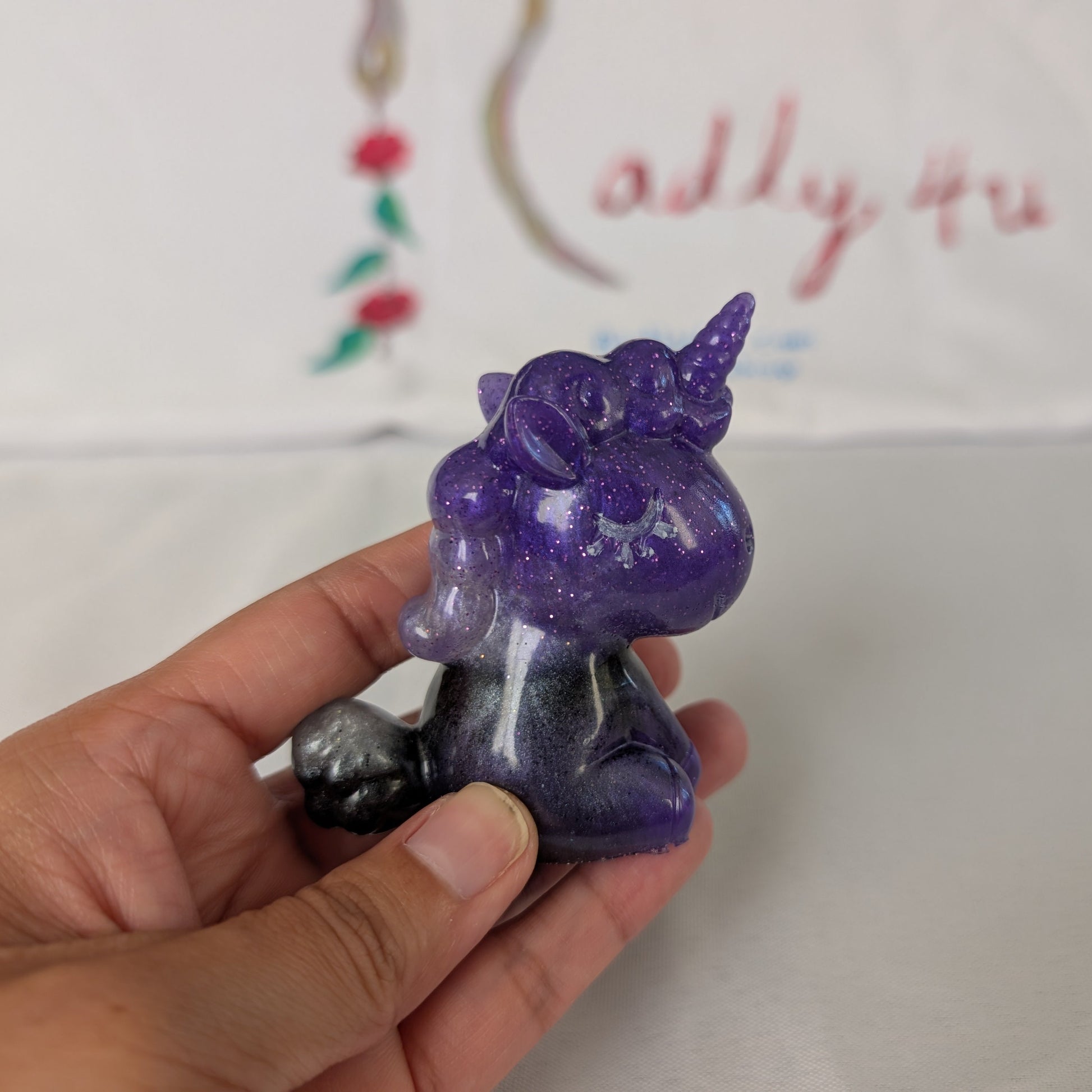 This whimsical resin unicorn is hand-crafted with glossy epoxy resin and detailed with vibrant acrylic paints. Its smooth, glass-like finish captures light beautifully, making it a charming little companion on your desk or shelf.