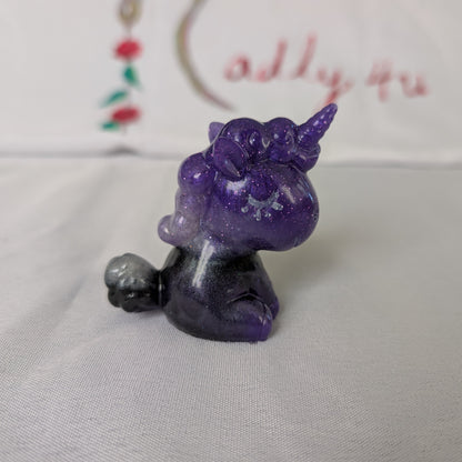 This whimsical resin unicorn is hand-crafted with glossy epoxy resin and detailed with vibrant acrylic paints. Its smooth, glass-like finish captures light beautifully, making it a charming little companion on your desk or shelf.