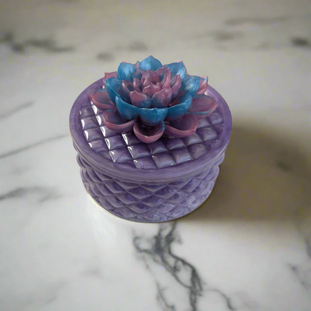 Keep your tiniest treasures safe in our round trinket box. With a charming resin design and a beautiful flower lid, it adds a playful touch to any space. At approximately 5 x 5 in, 4.25 in height, and weighing 11.7 oz, it's perfect for your precious items.