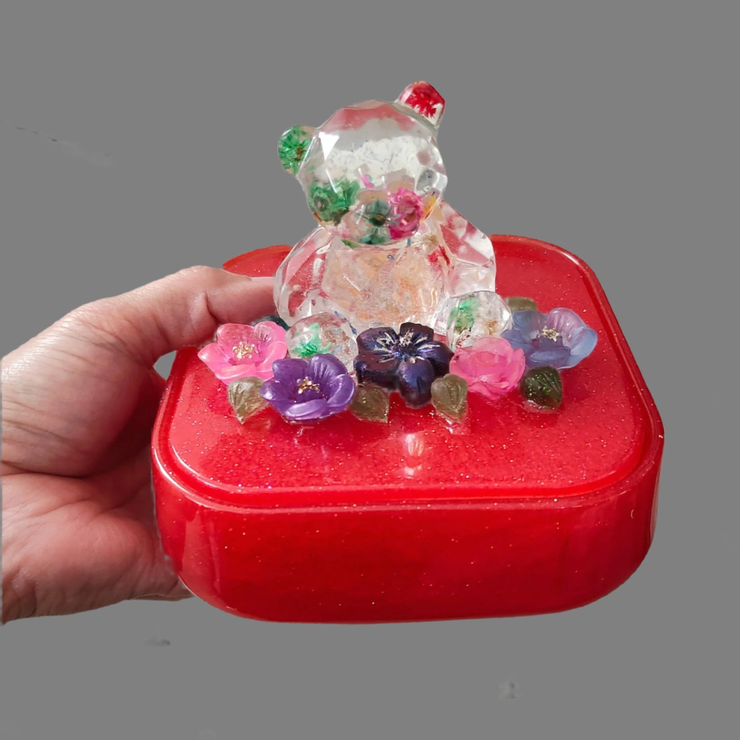 Elevate your jewelry storage with our Knickknack - Large resin square box! Featuring a charming bear and flowers lid, it adds a whimsical touch to any room. Boasting ample space for your precious items, it's the perfect blend of function and beauty. Upgrade to this stunning jewelry box today!