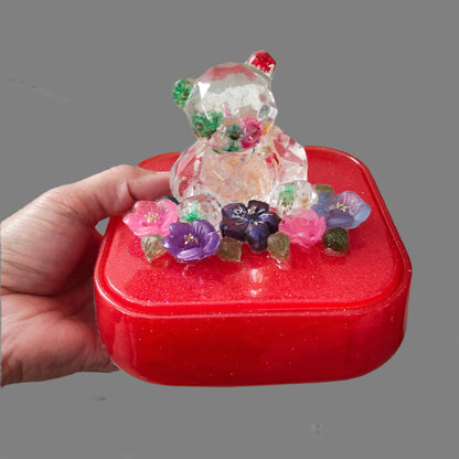 Elevate your jewelry storage with our Knickknack - Large resin square box! Featuring a charming bear and flowers lid, it adds a whimsical touch to any room. Boasting ample space for your precious items, it's the perfect blend of function and beauty. Upgrade to this stunning jewelry box today!