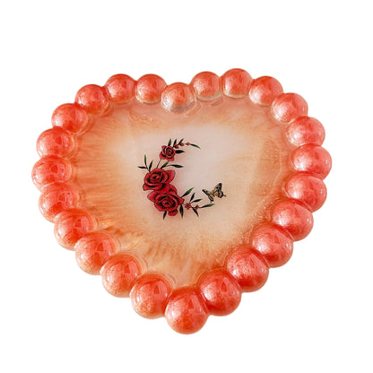 Elevate your space with our Resin Heart Trinket Tray. Formed into a heart shape, this tray is perfect for holding and displaying your small trinkets and treasures. Made of durable resin, it adds a touch of charm to any room while keeping your items organized and easily accessible.