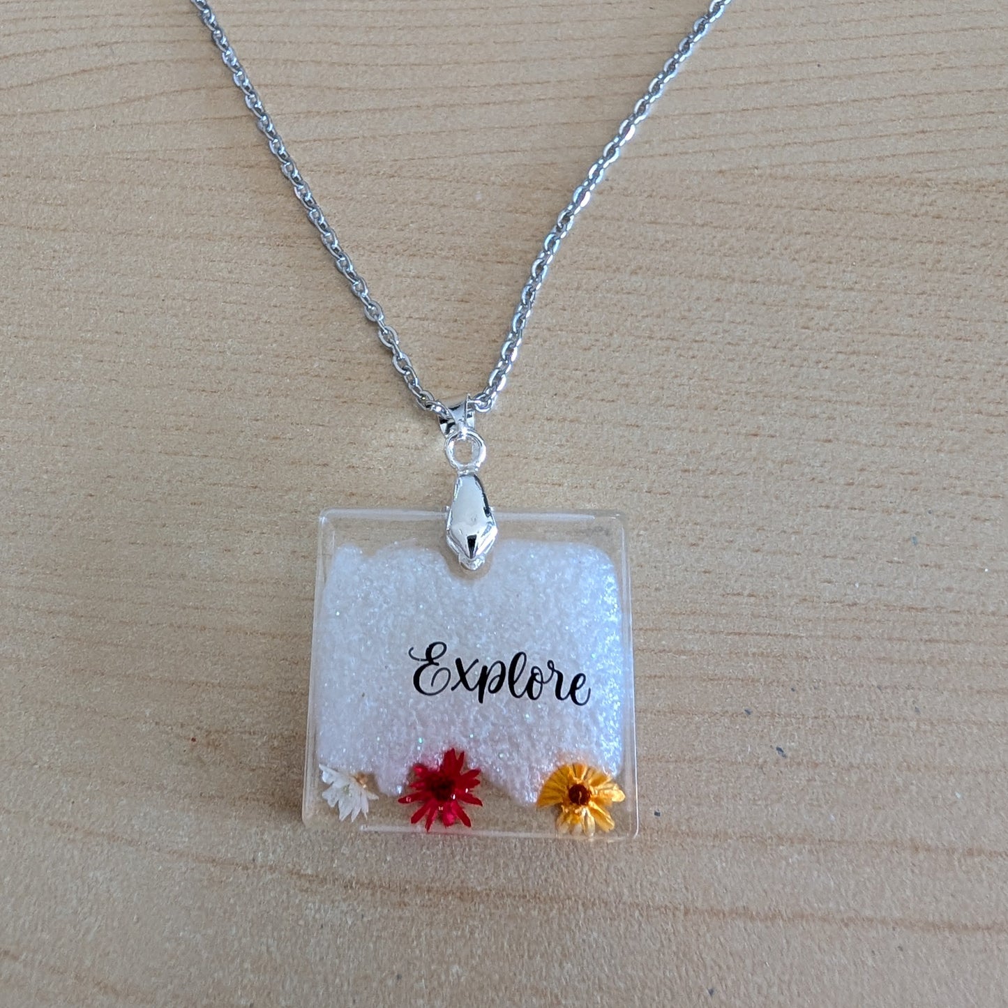 This stainless steel cable link chain necklace features a beautiful square pendant with real flowers embedded in resin. The necklace is 21 inches long, with an additional 2 inch extension chain. Make a statement with this one-of-a-kind piece!

Necklace - 21 inches stainless steel cable link chain with a resin with flowers square pendant