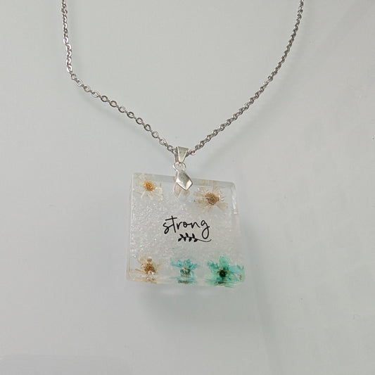 This stainless steel cable link chain necklace features a beautiful square pendant with real flowers embedded in resin. The necklace is 21 inches long, with an additional 2 inch extension chain. Make a statement with this one-of-a-kind piece!

Necklace - 21 inches stainless steel cable link chain with a resin with flowers square pendant