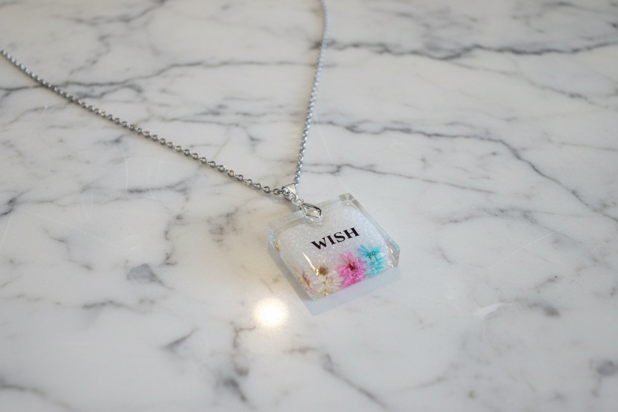 This stainless steel cable link chain necklace features a beautiful square pendant with real flowers embedded in resin. The necklace is 21 inches long, with an additional 2 inch extension chain. Make a statement with this one-of-a-kind piece!

Necklace - 21 inches stainless steel cable link chain with a resin with flowers square pendant