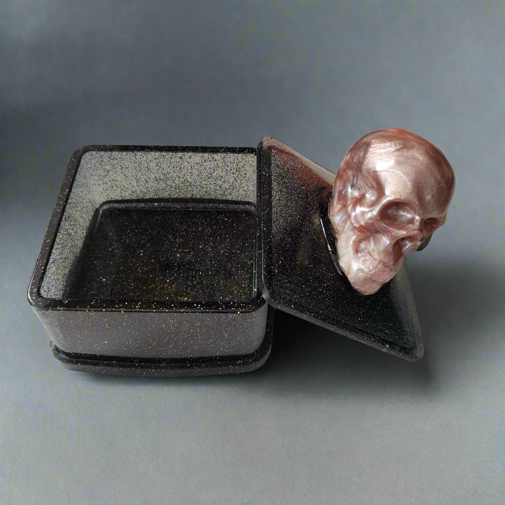 Say goodbye to boring trinket boxes and hello to this quirky Knickknack! Made of sturdy resin, it features a skull lid that adds a touch of spookiness to your decor. With dimensions of 3 x 3 x 3.5 inches and weighing only 5 oz, it's perfect for storing your knickknacks in style.

Resin square jewelry/trinket box with skull lid