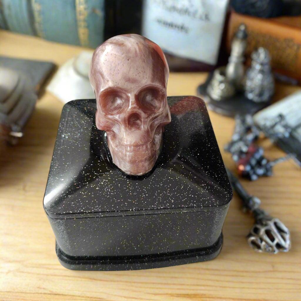 Say goodbye to boring trinket boxes and hello to this quirky Knickknack! Made of sturdy resin, it features a skull lid that adds a touch of spookiness to your decor. With dimensions of 3 x 3 x 3.5 inches and weighing only 5 oz, it's perfect for storing your knickknacks in style.

Resin square jewelry/trinket box with skull lid