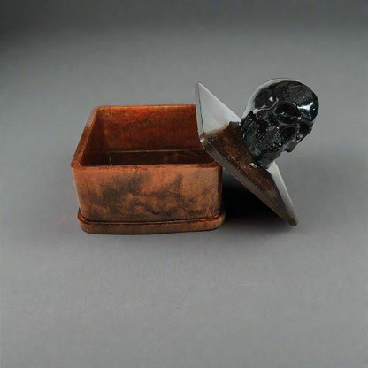 Say goodbye to boring trinket boxes and hello to this quirky Knickknack! Made of sturdy resin, it features a skull lid that adds a touch of spookiness to your decor. With dimensions of 3 x 3 x 3.5 inches and weighing only 5 oz, it's perfect for storing your knickknacks in style.

Resin square jewelry/trinket box with skull lid