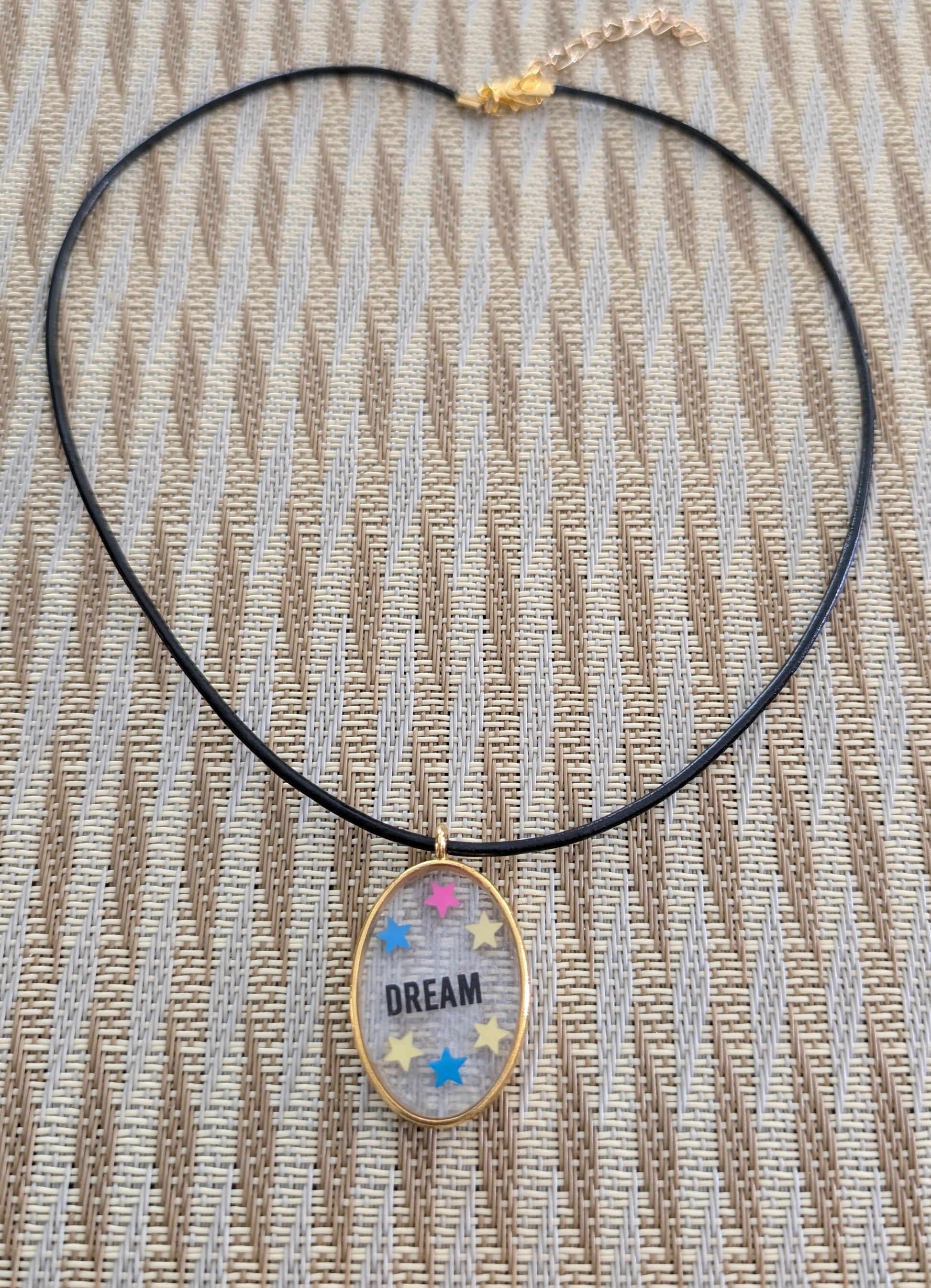 Indulge in the dreamy beauty of our 18 inch resin and stars gold oval pendant necklace. The stunning design is complemented by a 2mm black leather cord and adjustable extension chain. Weighing only 0.2 oz, it's lightweight and comfortable to wear. Elevate your style with this unique and charming accessory.