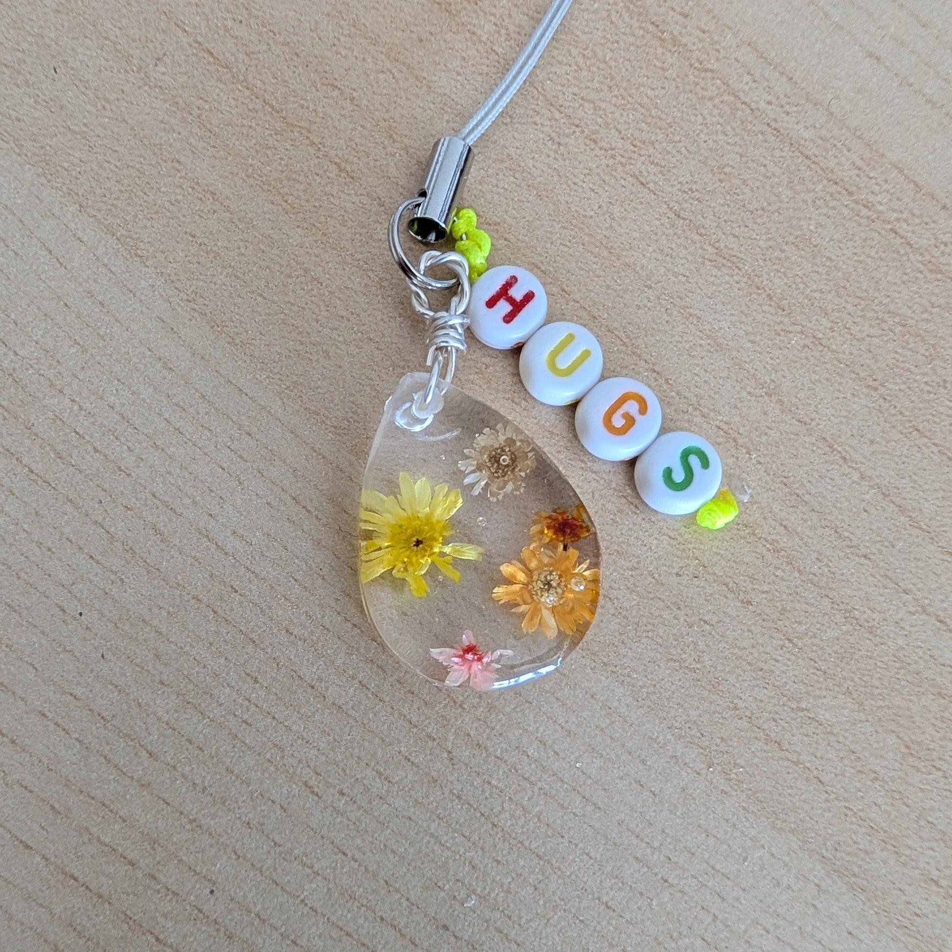 Spice up your phone with this charming resin charm, adorned with real dried flowers and beads. The 3.75 inch length adds a touch of flair to any device. (It's like a bouquet, but for your phone!)