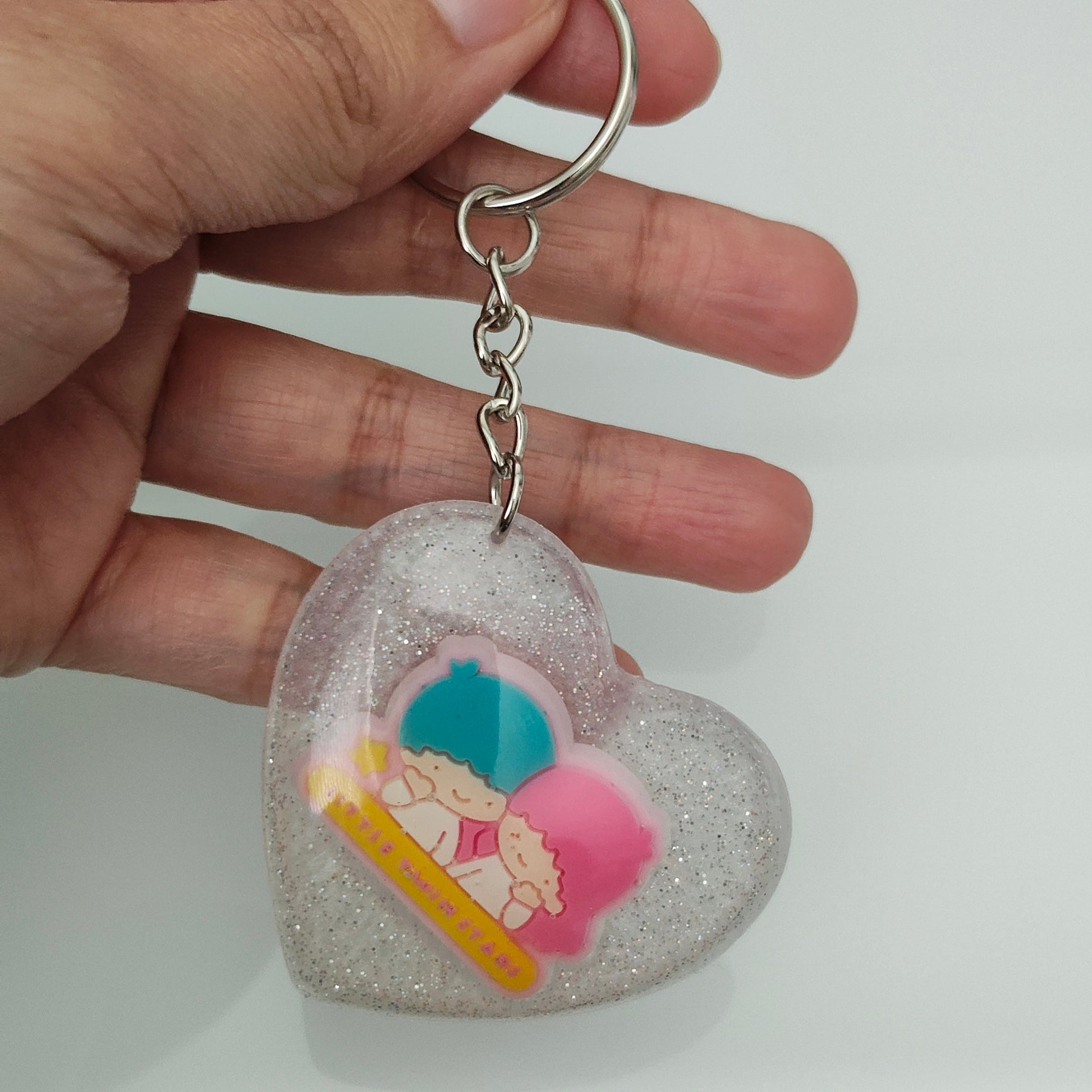 This 3D resin Kiki & Lala heart keychain is a must-have accessory for any fan of the beloved characters. The intricate design and vibrant colors are sure to catch the eyes and hearts of all who see it. Carry your keys with style and show off your love for Kiki & Lala with this charming keychain!