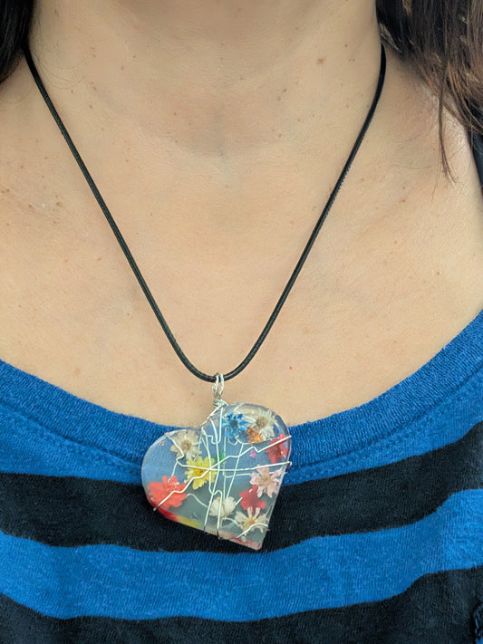 This stunning necklace features a heart-shaped pendant made of clear resin and real dried flowers, delicately suspended on a black cord. Measuring at 17.5 inches (plus a 2-inch extension chain), this unique piece adds a touch of nature and charm to any outfit.

Necklace - 17.5 inches clear resin with dried flowers heart on black cord