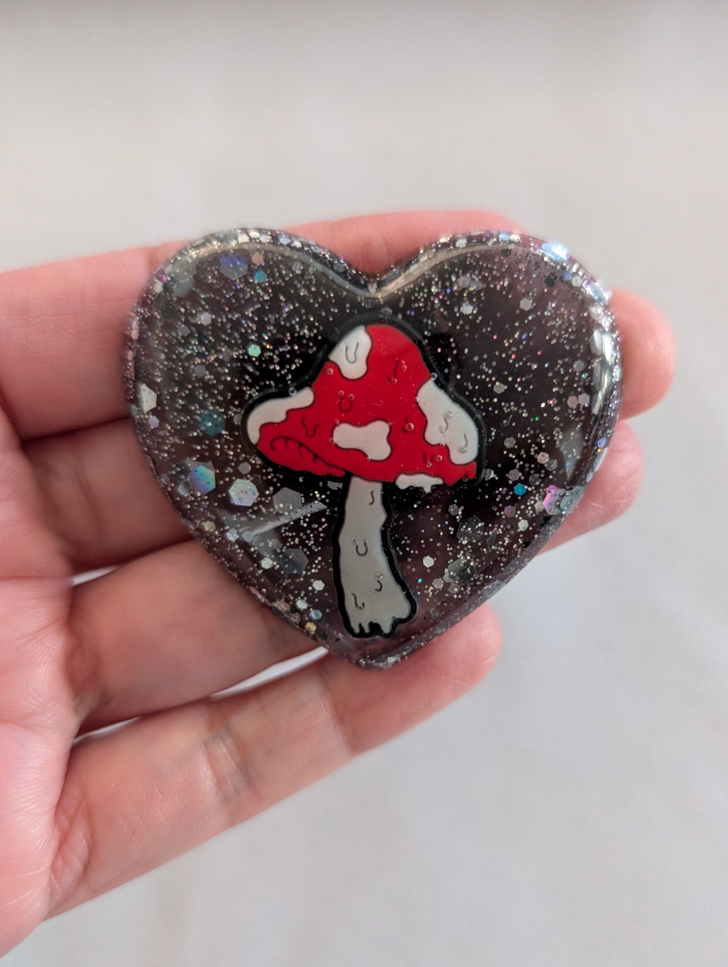 Bring a touch of whimsy to your space with this charming Mushroom Resin Heart Magnet. Perfectly sized at 1.75 x 2 inches, this lightweight magnet (just 0.47 oz) features an enchanting mushroom design captured in beautiful resin. Ideal for refrigerators, lockers, or any magnetic surface, it adds personality and a pop of nature-inspired charm to your everyday décor. A delightful gift for mushroom lovers and resin art enthusiasts alike.