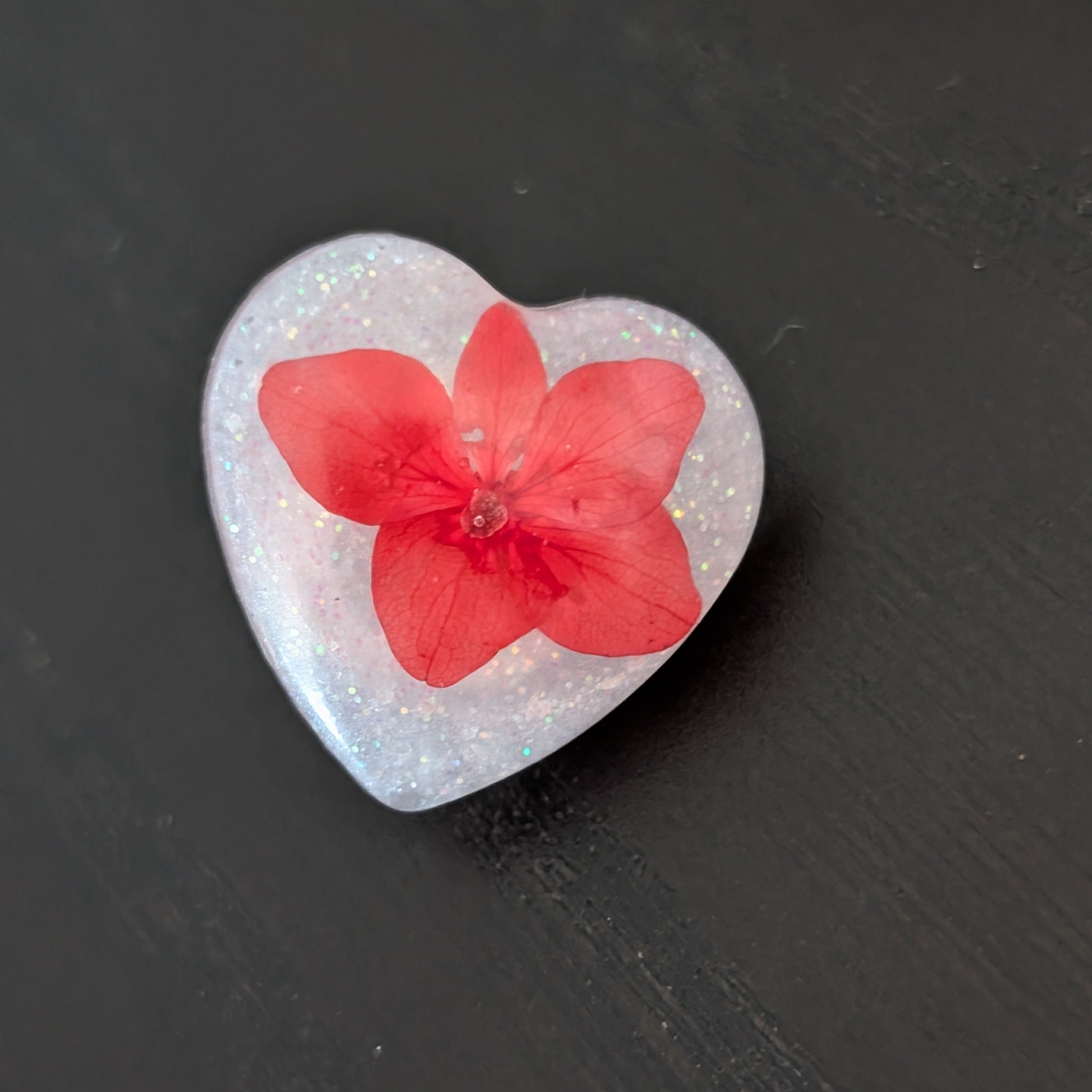 Add a touch of nature to your outfit with our Pin - 3D dried flower resin pin. The intricate design and 3D effect will surely catch everyone's eye. With the sturdy silver butterfly clutch, your pin will stay securely in place. Elevate your style with this unique and beautiful accessory.