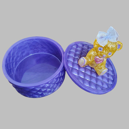 This adorable hand-crafted resin trinket box brings a touch of whimsy to your space! Featuring a charming teddy bear perched on top, it's the perfect home for jewelry, keepsakes, or small treasures. Measuring 5" x 5" x 5" with a 2" deep dish, this compact beauty combines functionality with personality. Crafted from smooth, durable epoxy resin that feels like glass, it's built to last while adding a playful accent to any dresser or shelf. At just 13 oz, it's lightweight enough to move around but sturdy enoug