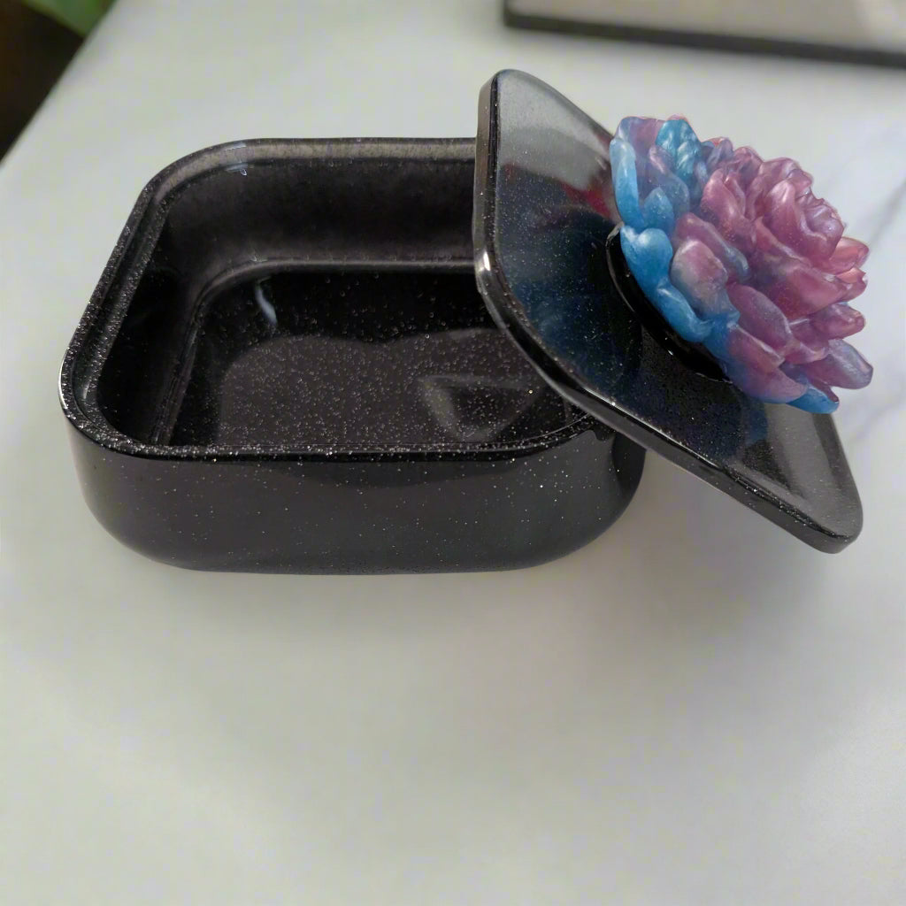 Elevate your jewelry collection with this stunning Knickknack jewelry box. Featuring a flower lid and made of durable resin, this box measures 5 x 5 inches and has a depth of 1.5 inches, making it perfect for large pieces. Weighing only 14 oz, it's also lightweight and easy to transport. Transform your dressing table and protect your precious pieces with this beautiful box.