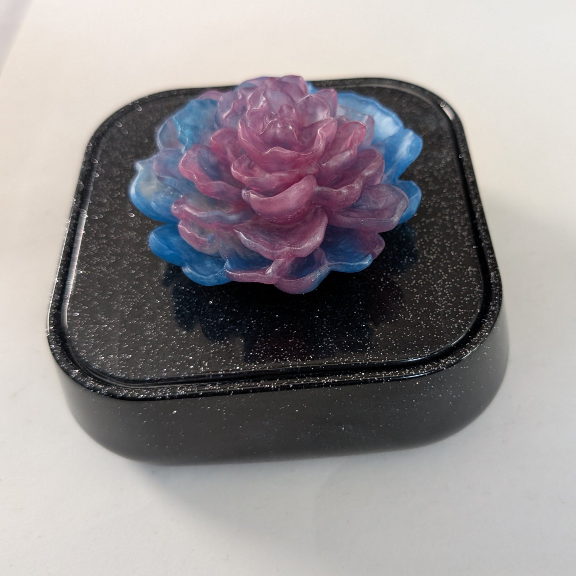 Elevate your jewelry collection with this stunning Knickknack jewelry box. Featuring a flower lid and made of durable resin, this box measures 5 x 5 inches and has a depth of 1.5 inches, making it perfect for large pieces. Weighing only 14 oz, it's also lightweight and easy to transport. Transform your dressing table and protect your precious pieces with this beautiful box.