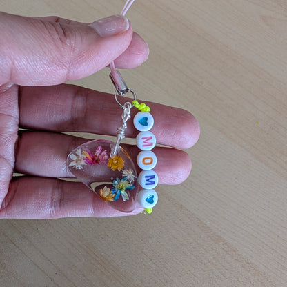 Spice up your phone with this charming resin charm, adorned with real dried flowers and beads. The 3.75 inch length adds a touch of flair to any device. (It's like a bouquet, but for your phone!)

Phone charm - Resin charm with dried flowers and beads