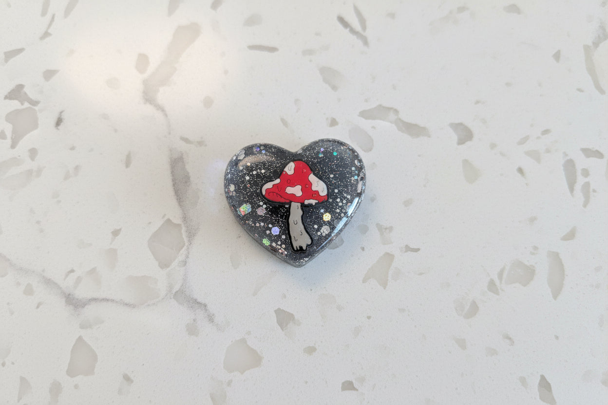 Bring a touch of whimsy to your space with this charming Mushroom Resin Heart Magnet. Perfectly sized at 1.75 x 2 inches, this lightweight magnet (just 0.47 oz) features an enchanting mushroom design captured in beautiful resin. Ideal for refrigerators, lockers, or any magnetic surface, it adds personality and a pop of nature-inspired charm to your everyday décor. A delightful gift for mushroom lovers and resin art enthusiasts alike.