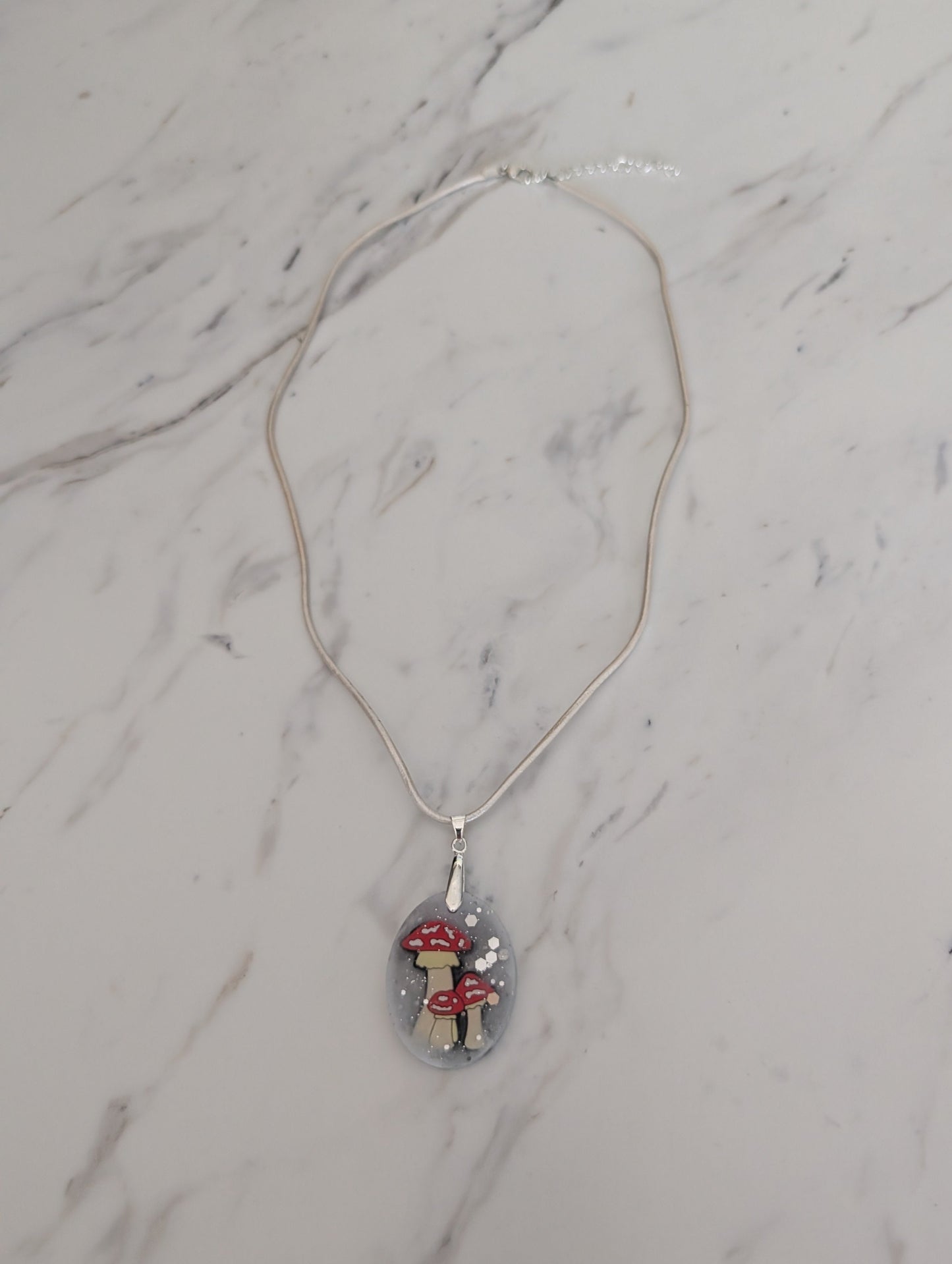 Necklace with a pendant featuring mushrooms on a marble surface