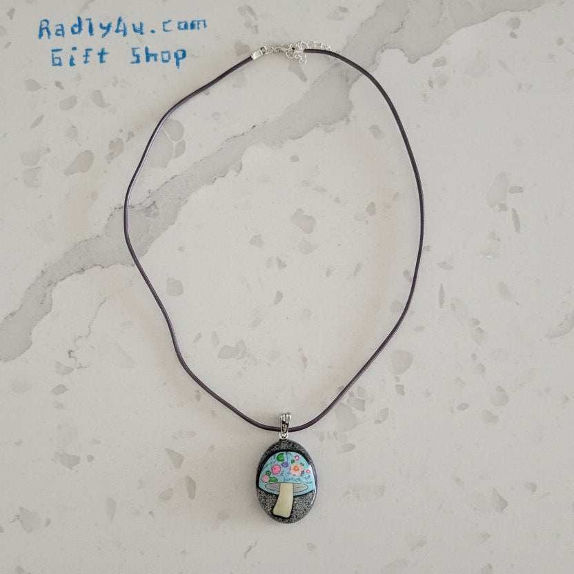 Necklace with a pendant featuring a mushroom design on a textured surface.