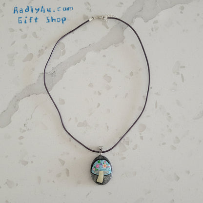 Necklace with a pendant featuring a mushroom design on a textured surface.