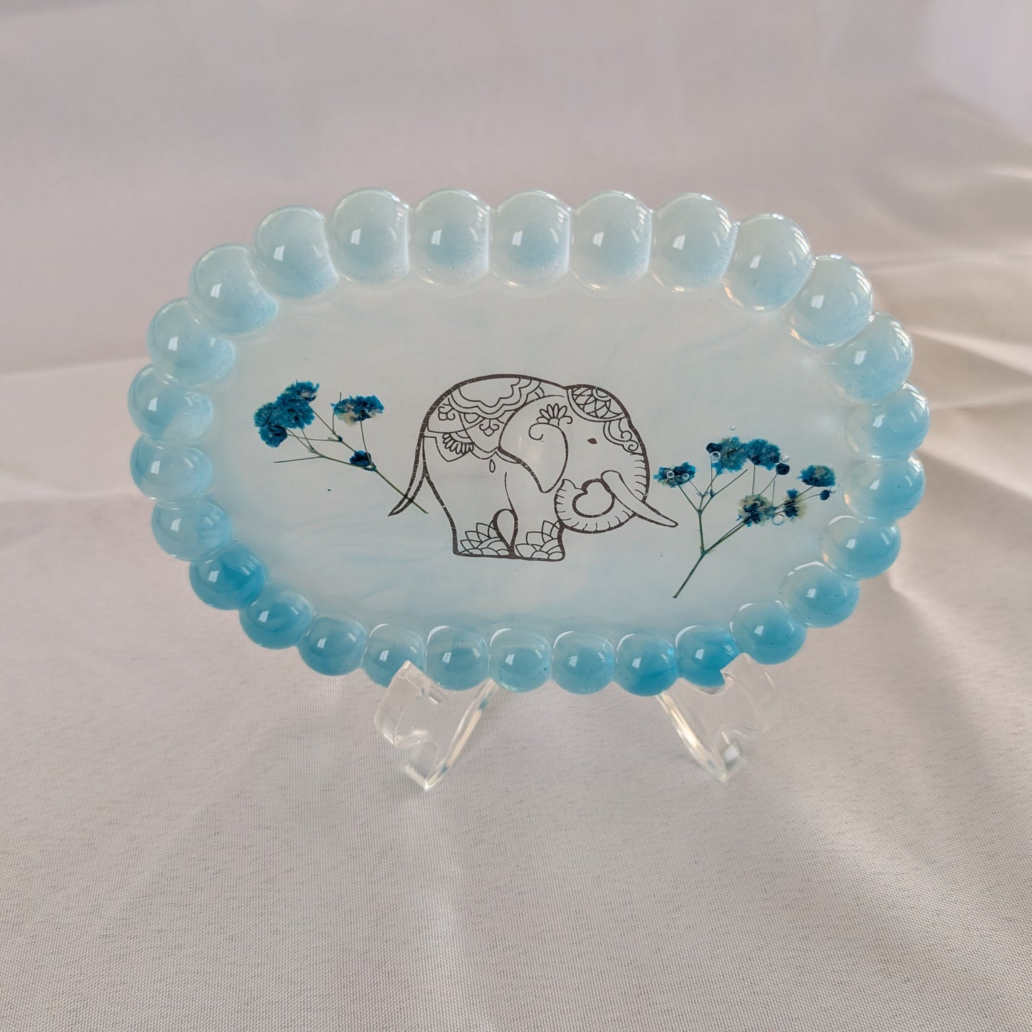 Organize and display your trinkets in style with our Resin Oval jewelry/Trinket Tray. Made from durable resin, this tray adds a touch of elegance to any space. Its unique oval shape and smooth finish make it perfect for storing your small items. Keep your trinkets safe and organized with this beautiful tray!