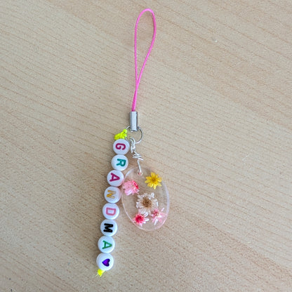 Spice up your phone with this charming resin charm, adorned with real dried flowers and beads. The 3.75 inch length adds a touch of flair to any device. (It's like a bouquet, but for your phone!)

Phone charm - Resin charm with dried flowers and beads