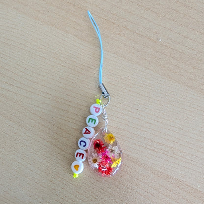 Spice up your phone with this charming resin charm, adorned with real dried flowers and beads. The 3.75 inch length adds a touch of flair to any device. (It's like a bouquet, but for your phone!)

Phone charm - Resin charm with dried flowers and beads