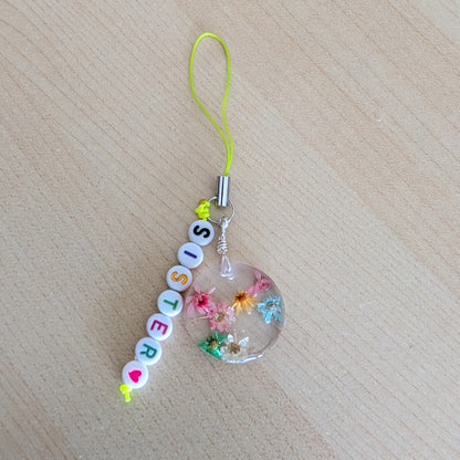 Spice up your phone with this charming resin charm, adorned with real dried flowers and beads. The 3.75 inch length adds a touch of flair to any device. (It's like a bouquet, but for your phone!)

Phone charm - Resin charm with dried flowers and beads