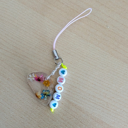 Spice up your phone with this charming resin charm, adorned with real dried flowers and beads. The 3.75 inch length adds a touch of flair to any device. (It's like a bouquet, but for your phone!)

Phone charm - Resin charm with dried flowers and beads
