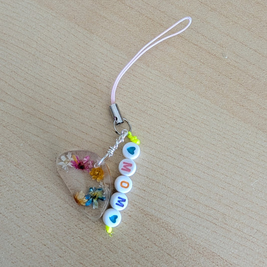Spice up your phone with this charming resin charm, adorned with real dried flowers and beads. The 3.75 inch length adds a touch of flair to any device. (It's like a bouquet, but for your phone!)

Phone charm - Resin charm with dried flowers and beads