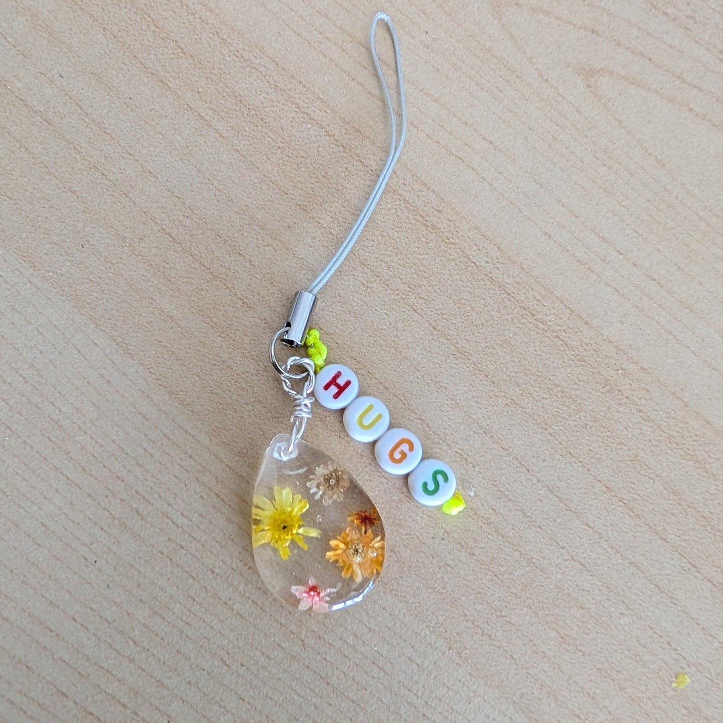 Spice up your phone with this charming resin charm, adorned with real dried flowers and beads. The 3.75 inch length adds a touch of flair to any device. (It's like a bouquet, but for your phone!)