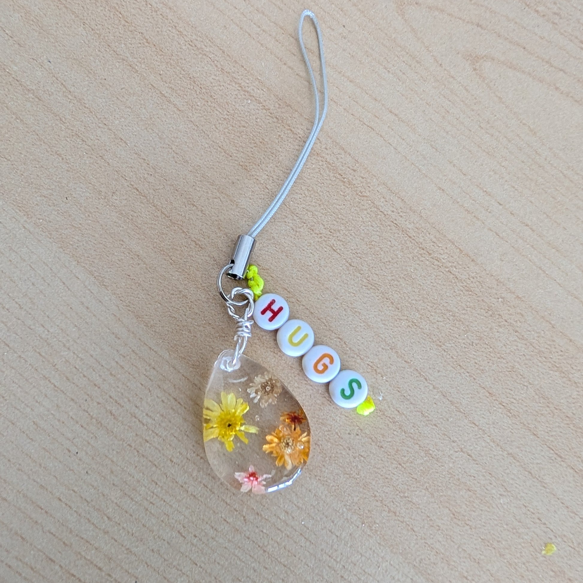 Spice up your phone with this charming resin charm, adorned with real dried flowers and beads. The 3.75 inch length adds a touch of flair to any device. (It's like a bouquet, but for your phone!)