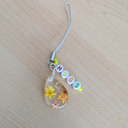 Spice up your phone with this charming resin charm, adorned with real dried flowers and beads. The 3.75 inch length adds a touch of flair to any device. (It's like a bouquet, but for your phone!)