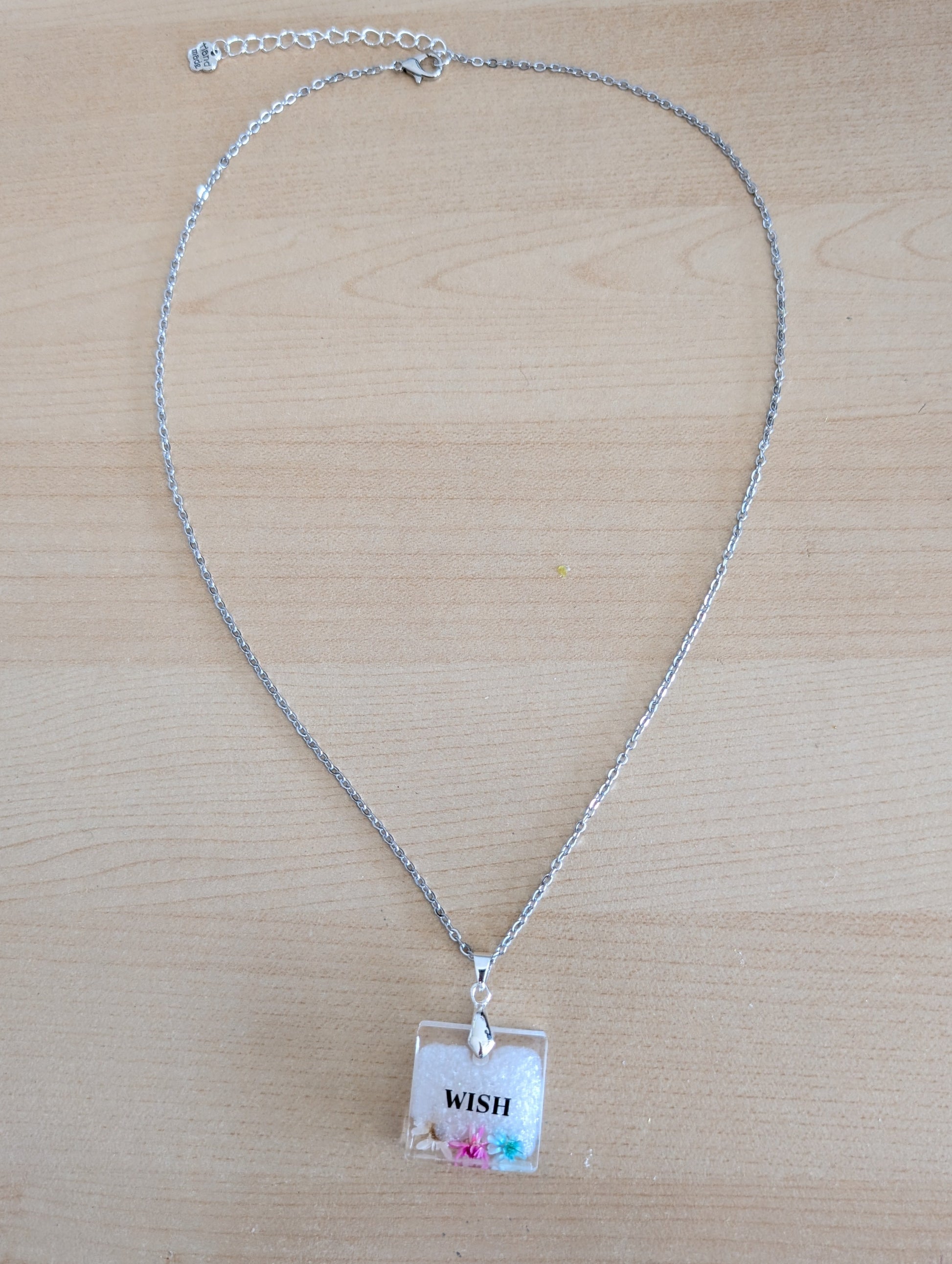 This stainless steel cable link chain necklace features a beautiful square pendant with real flowers embedded in resin. The necklace is 21 inches long, with an additional 2 inch extension chain. Make a statement with this one-of-a-kind piece!

Necklace - 21 inches stainless steel cable link chain with a resin with flowers square pendant
