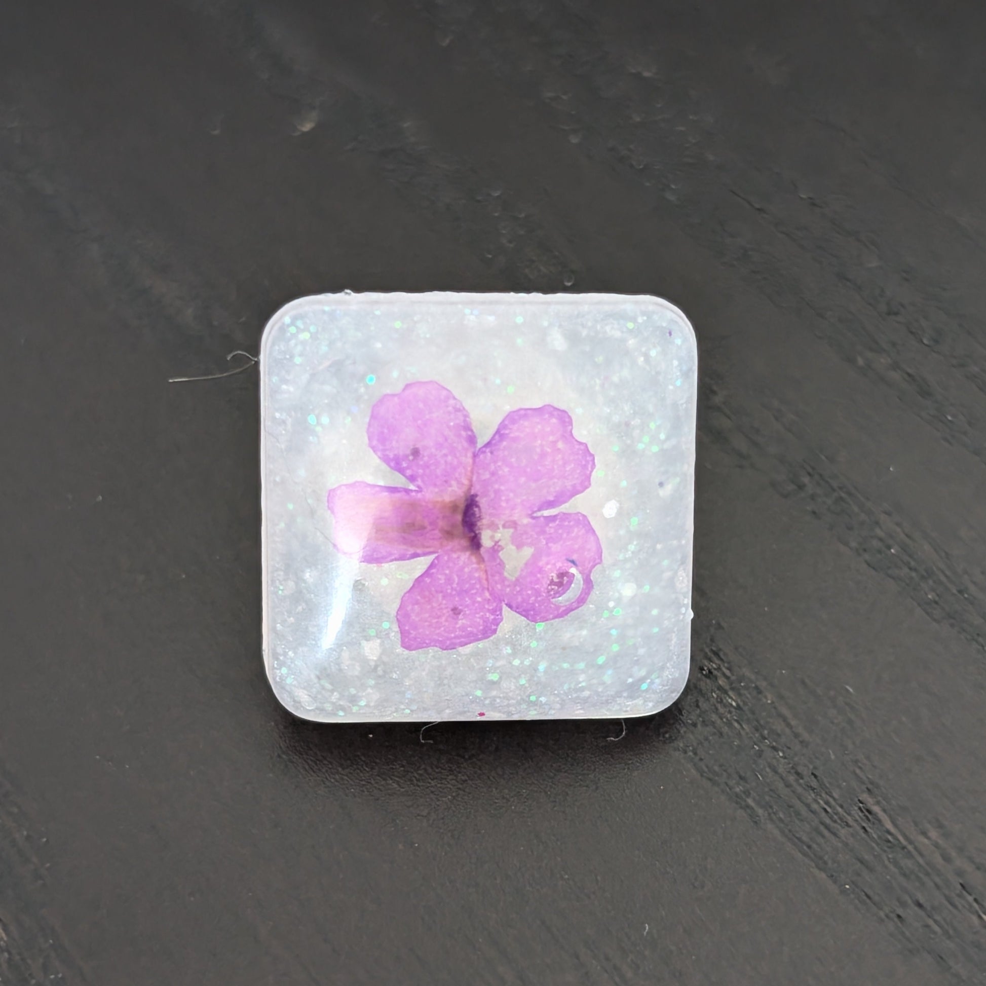 Add a touch of nature to your outfit with our Pin - 3D dried flower resin pin. The intricate design and 3D effect will surely catch everyone's eye. With the sturdy silver butterfly clutch, your pin will stay securely in place. Elevate your style with this unique and beautiful accessory.