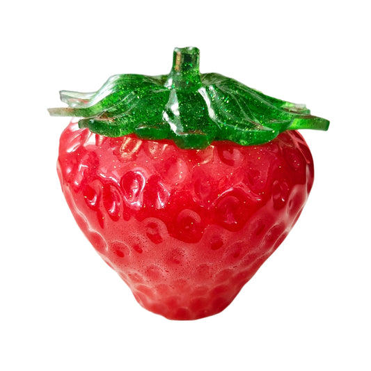 A red resin strawberry trinket with a green lid, resembling a decorative fruit.