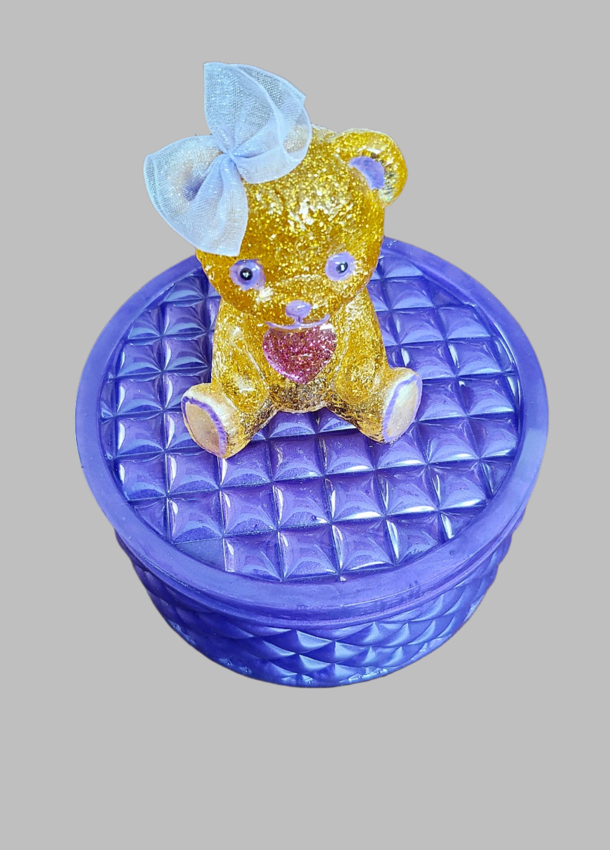 This adorable hand-crafted resin trinket box brings a touch of whimsy to your space! Featuring a charming teddy bear perched on top, it's the perfect home for jewelry, keepsakes, or small treasures. Measuring 5" x 5" x 5" with a 2" deep dish, this compact beauty combines functionality with personality. Crafted from smooth, durable epoxy resin that feels like glass, it's built to last while adding a playful accent to any dresser or shelf. At just 13 oz, it's lightweight enough to move around but sturdy enoug
