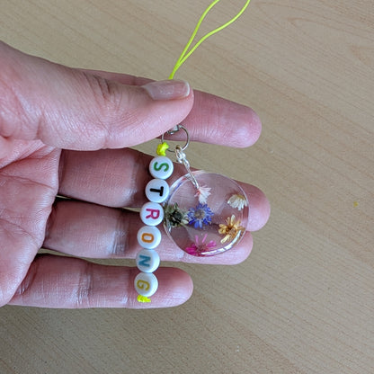 Spice up your phone with this charming resin charm, adorned with real dried flowers and beads. The 3.75 inch length adds a touch of flair to any device. (It's like a bouquet, but for your phone!)

Phone charm - Resin charm with dried flowers and beads