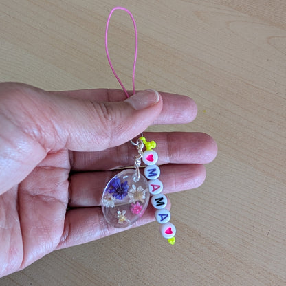 Spice up your phone with this charming resin charm, adorned with real dried flowers and beads. The 3.75 inch length adds a touch of flair to any device. (It's like a bouquet, but for your phone!)

Phone charm - Resin charm with dried flowers and beads