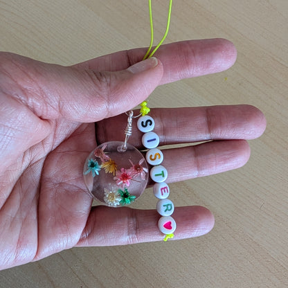 Spice up your phone with this charming resin charm, adorned with real dried flowers and beads. The 3.75 inch length adds a touch of flair to any device. (It's like a bouquet, but for your phone!)

Phone charm - Resin charm with dried flowers and beads