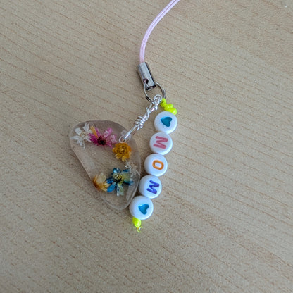 Spice up your phone with this charming resin charm, adorned with real dried flowers and beads. The 3.75 inch length adds a touch of flair to any device. (It's like a bouquet, but for your phone!)

Phone charm - Resin charm with dried flowers and beads