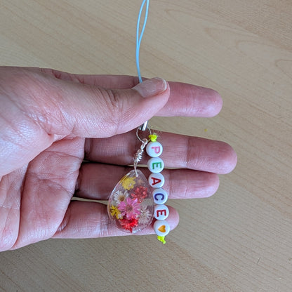 Spice up your phone with this charming resin charm, adorned with real dried flowers and beads. The 3.75 inch length adds a touch of flair to any device. (It's like a bouquet, but for your phone!)

Phone charm - Resin charm with dried flowers and beads