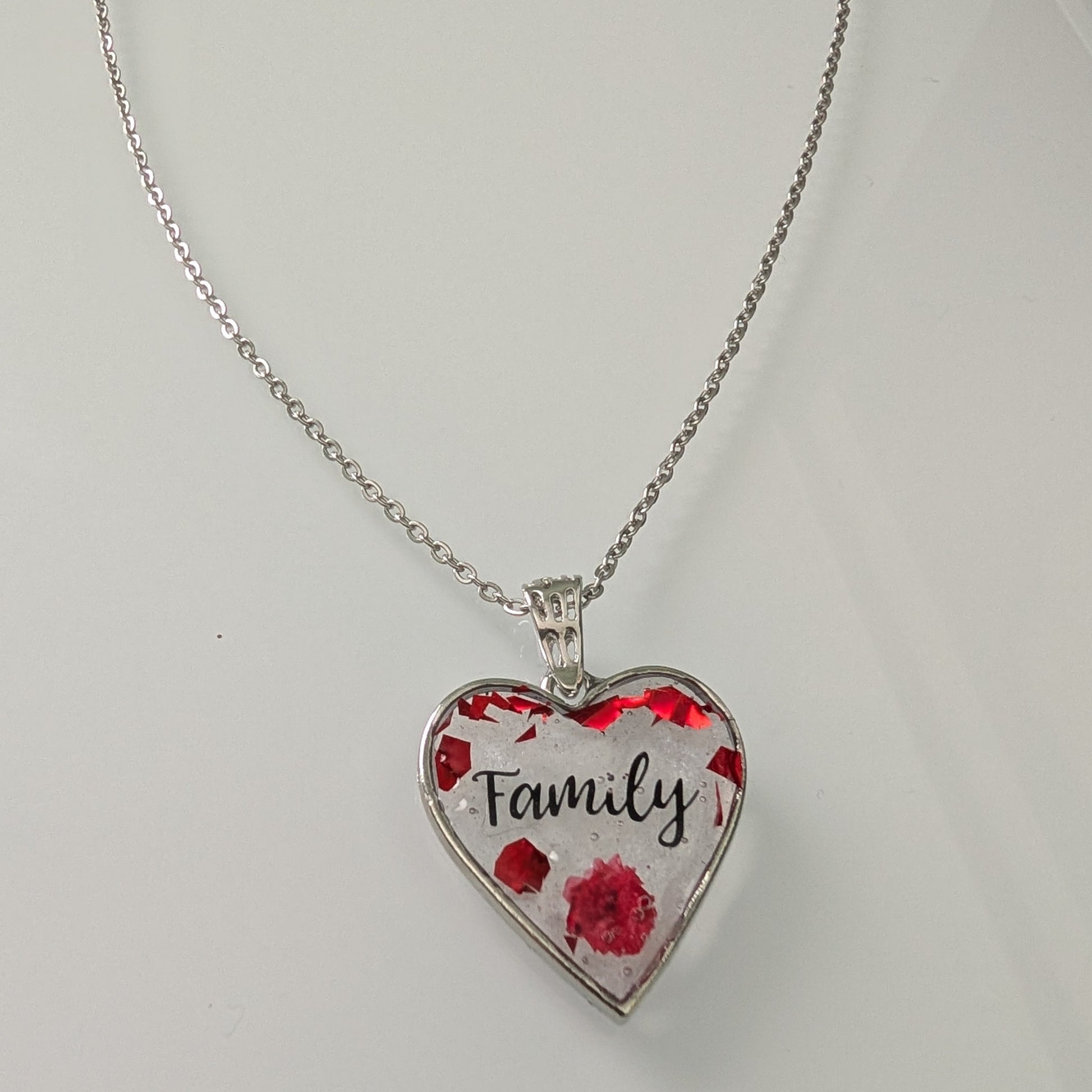 This stunning necklace features a 21-inch stainless steel cable link chain adorned with a beautiful family resin and flowers silver heart pendant. The perfect length for any outfit, with the option to add an additional 2 inches for the perfect fit. Show your love and style with this unique piece!

Necklace - 21 inches stainless steel cable link chain with a family resin and flowers silver heart pendant
