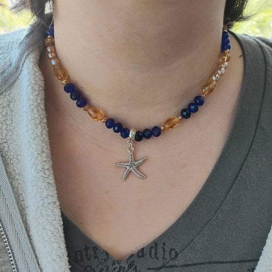 Add a touch of the ocean to your outfit with our Silver Starfish Necklace. Featuring a delicate silver starfish charm adorned with blue and gold crystal and glass beads, this necklace is perfect for any occasion. Choose between 16 and 18 inches for the perfect fit, and enjoy its lightweight design at only 0.72 oz.

Necklace - Silver starfish charm with blue and gold crystal and glass beads